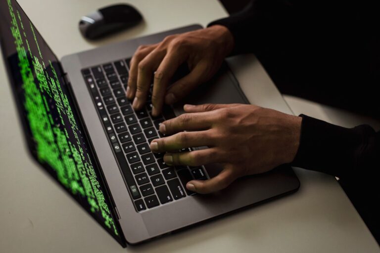Hands typing on a laptop with code on the screen