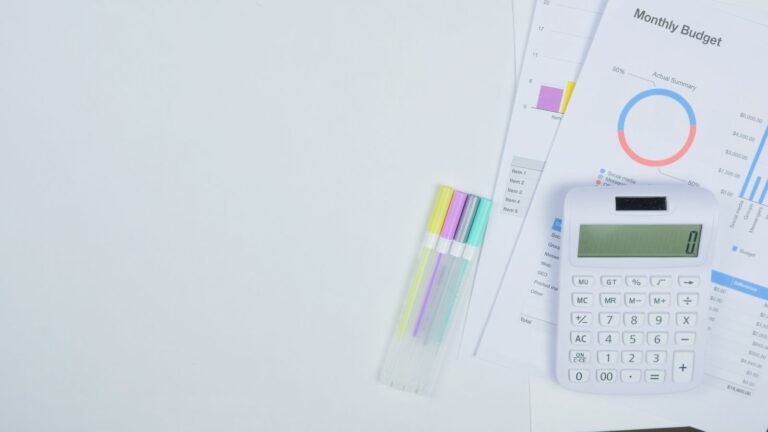 Monthly budget sheet with calculator and pens, planning a website cost