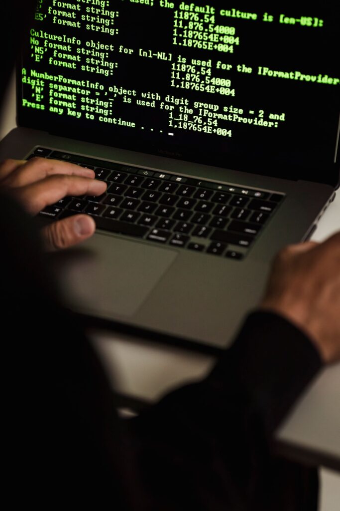 Person typing on a laptop showing lines of data