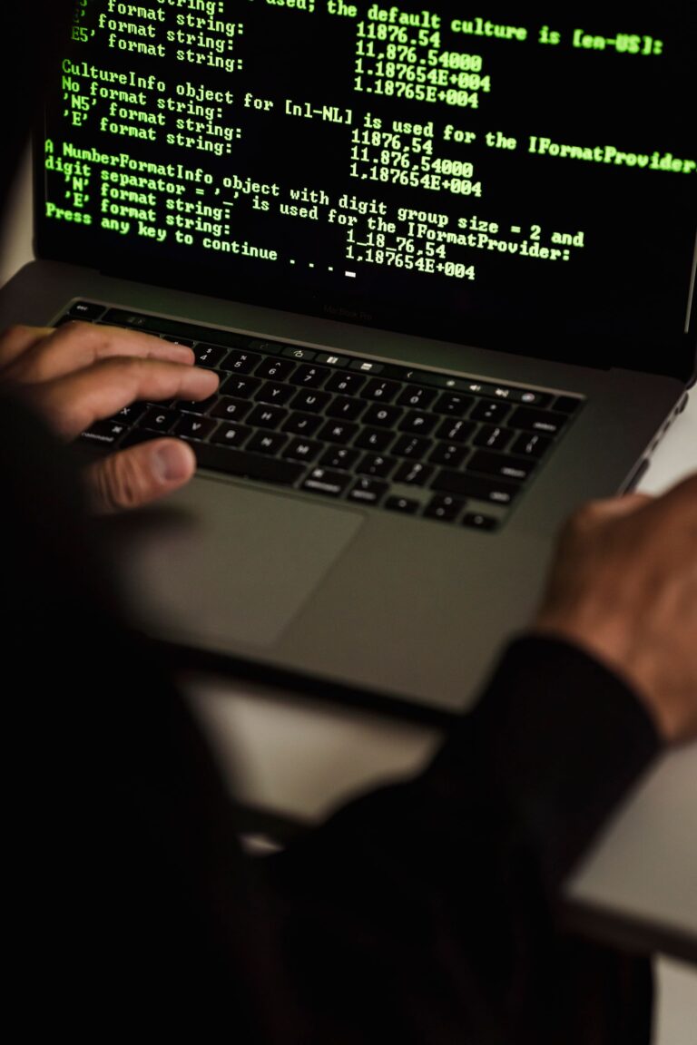 Person typing on a laptop showing lines of data